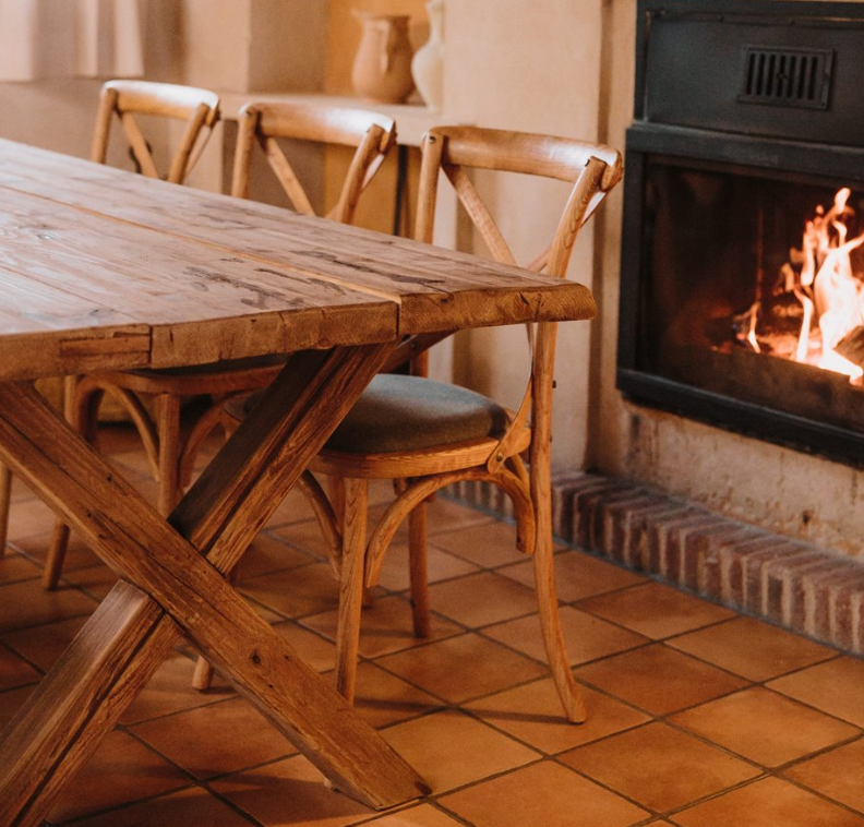 Sillas tapizadas en tonos cálidos con estructura de madera en comedor rústico junto a chimenea encendida